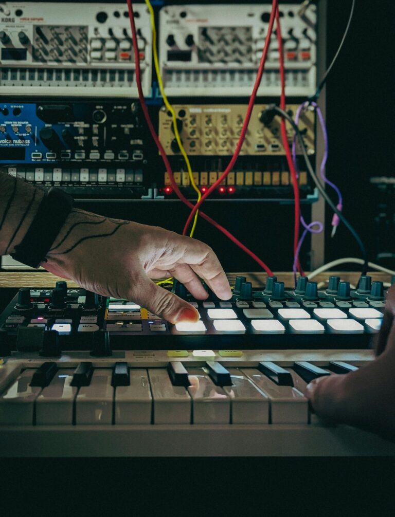 Close-up of hands managing synthesizer and mixer in a music production studio.